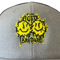 The Acid Brothers grey and back trucker cap with black and yellow embroidered 'smileys' logo.