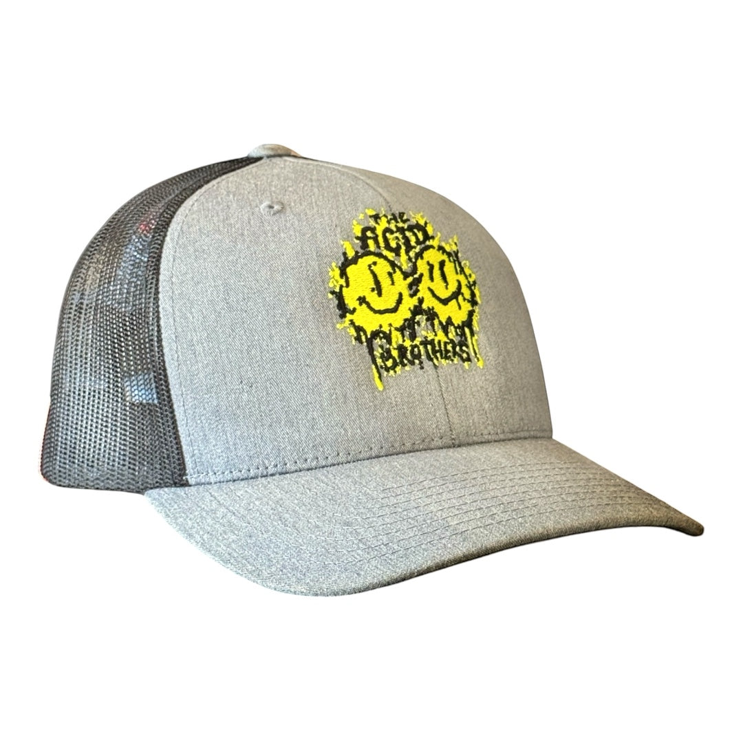 The Acid Brothers grey and back trucker cap with black and yellow embroidered 'smileys' logo.