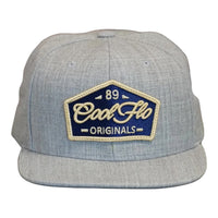 Front view of a Cool Flo 89 Originals snapback cap in Heather Grey featuring an embroidered 89 Originals badge in Navy, Gold and White and a flat visor