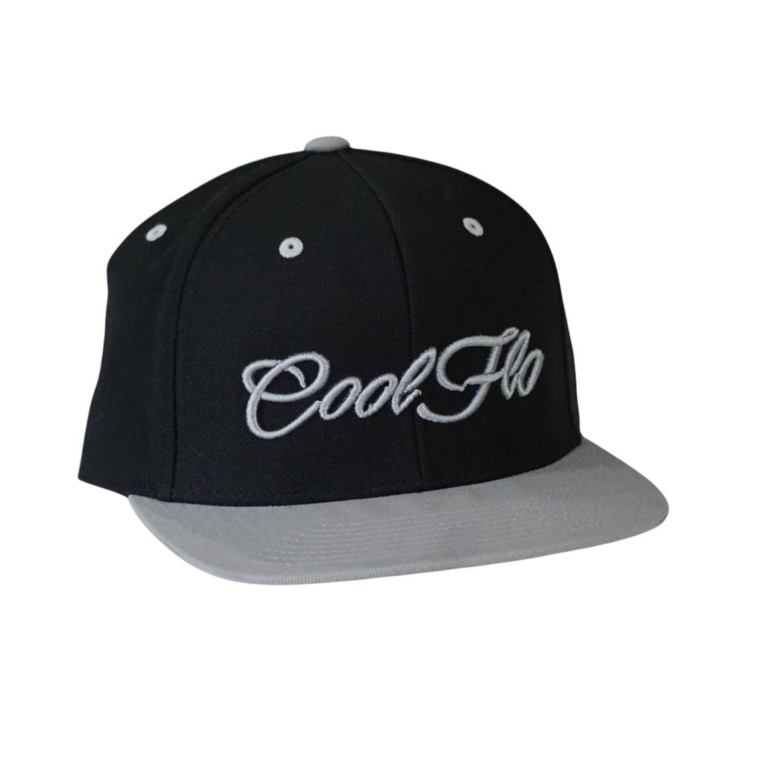 Two tone black and silver snapback cap with embroidered 3D script logo in silver on the front. 