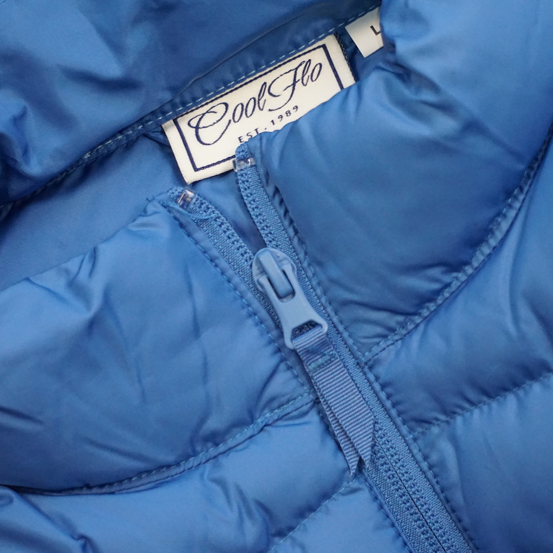 Close-up of neck/zip on premium blue puffer jacket with matching Cool Flo script logo embroidered on the left.