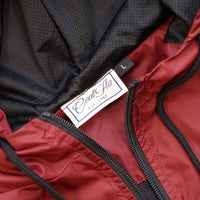 Close-up of neck and zip detail on Burgundy and black wind runner jacket with black Cool Flo script logo embroidered on the left.