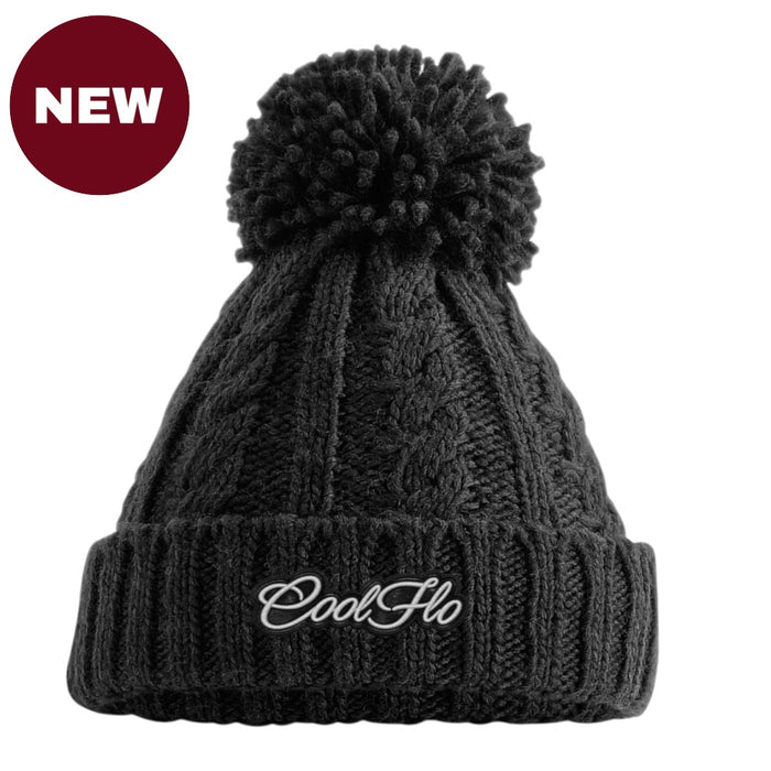 A black cable-knit pom-pom beanie with a white embroidered 'CoolFlo' logo on the front cuff, shown on a white background with a red 'NEW' badge in the top-left corner.