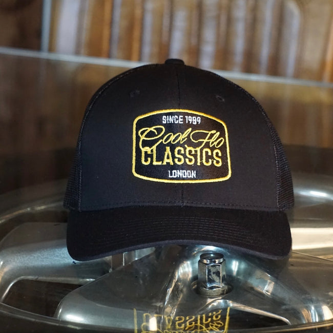 Cool Flo Classics black trucker cap with white yellow and black embroidered badge design.