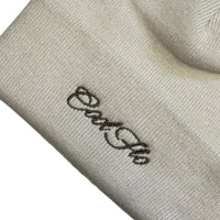 Close-up of Cool Flo Cuffed Beanie Hat in an almond colour with a brown Cool Flo embroidered logo on the cuff.