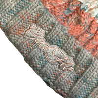 Close-up of Cool Flo Morzine bobble hat in Sunrise Mist colour way with an embroidered logo on the cuff.