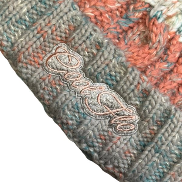 Close-up of Cool Flo Morzine bobble hat in Sunrise Mist colour way with an embroidered logo on the cuff.