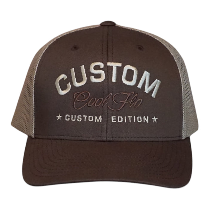 A dark brown custom trucker hat with  khaki mesh side panels. The front features white embroidered text reading 'CUSTOM' with 'Cool Flo' in cursive underneath and 'CUSTOM EDITION' with star accents.