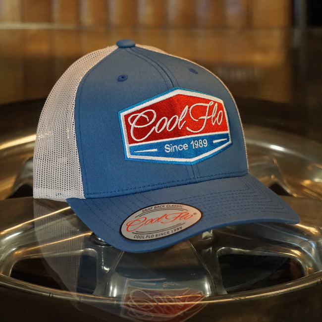 Cool Flo Blue and silver-grey two-tone trucker caps with turquoise, red and white embroidered badge design on the front.Cool Flo - Since 1989
