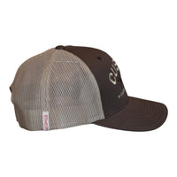 A dark brown custom trucker hat with  khaki mesh side panels. The front features white embroidered text reading 'CUSTOM' with 'Cool Flo' in cursive underneath and 'CUSTOM EDITION' with star accents.  The side view features a white Cool Flo loop tag with red script logo. 