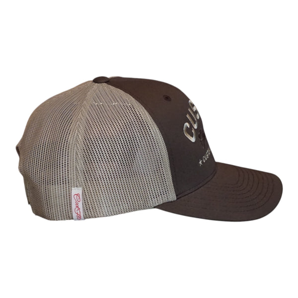 A dark brown custom trucker hat with  khaki mesh side panels. The front features white embroidered text reading 'CUSTOM' with 'Cool Flo' in cursive underneath and 'CUSTOM EDITION' with star accents.  The side view features a white Cool Flo loop tag with red script logo. 