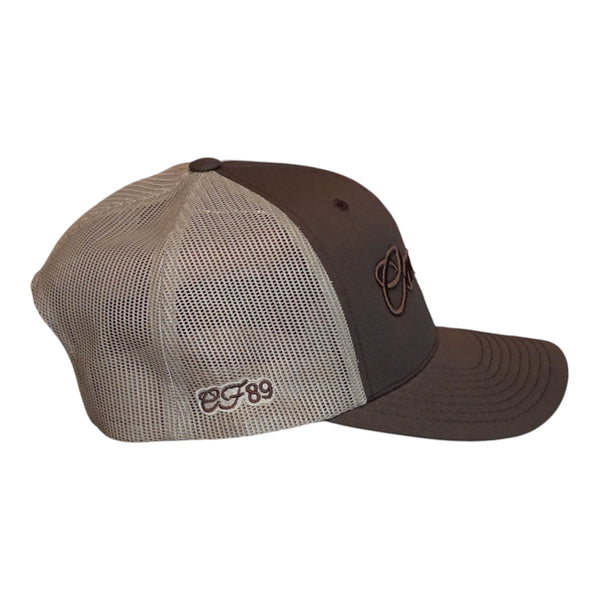 A brown and khaki trucker with a dark brown front panel and visor, khaki mesh back panels, and embroidered logos on the side and front.