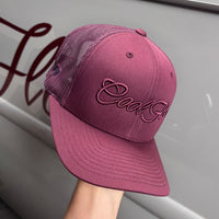 A burgundy trucker cap with 'Cool Flo' embroidered in matching burgundy script across the front, set against against a Cool Flo classic car.