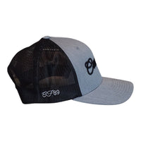 A two-tone trucker cap with a heather grey front panel and brim, black mesh back panels, and black embroidered Cool Flo Script logo on the front and grey embroidered 'CF89' on the side, shown on a plain white background.
