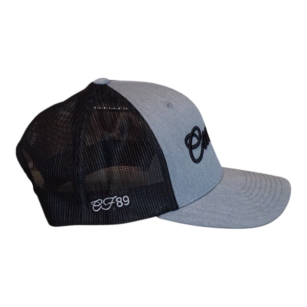 A two-tone trucker cap with a heather grey front panel and brim, black mesh back panels, and black embroidered Cool Flo Script logo on the front and grey embroidered 'CF89' on the side, shown on a plain white background.