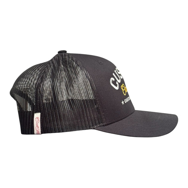 Cool Flo Custom Edition Black Trucker Cap with silver custom embroidery and yellow logo, side view.