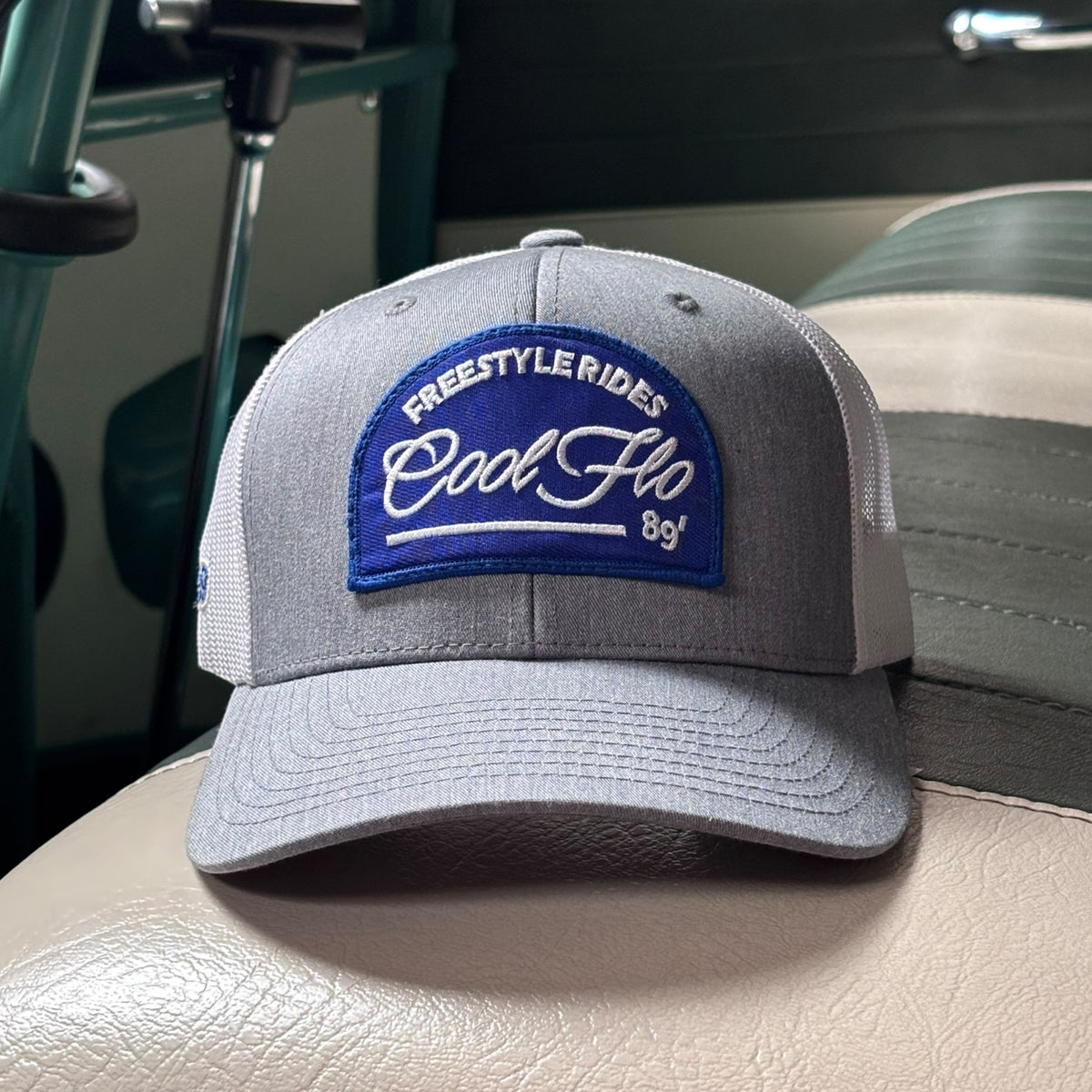 Front view of a Cool Flo Freestyle Rides trucker cap in Grey/White featuring an embroidered Freestyle Rides badge and curved visor