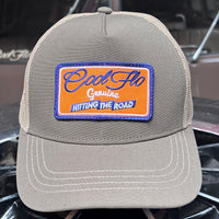 Front view of a Cool Flo Hitting The Road trucker cap in Olive/Khaki featuring an embroidered Hitting The Road badge in Orange, Blue and White and a curved visor