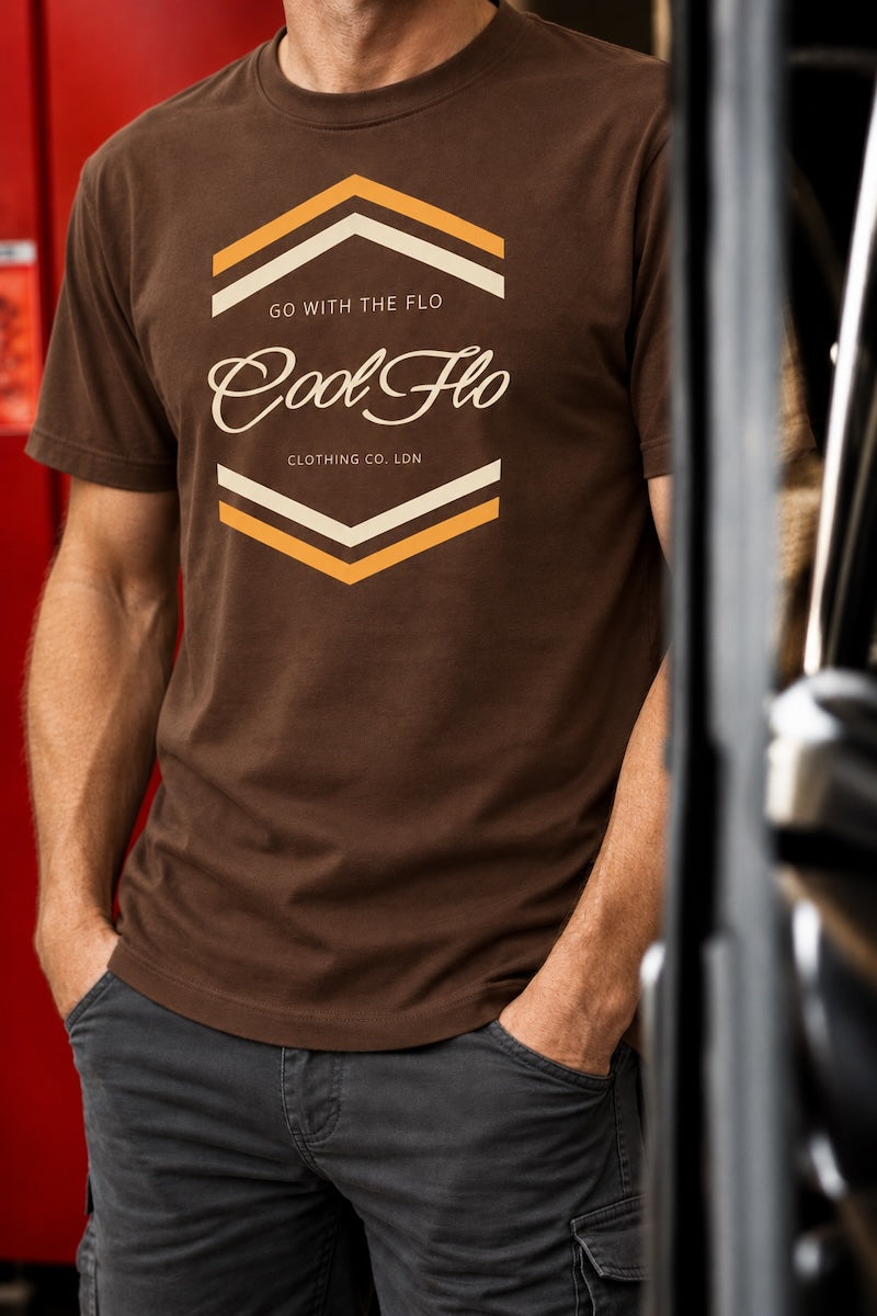 A model wearing a brown 'Chevron' graphic t-shirt with a 'Cool Flo' logo, standing in a garage with hands in pockets.