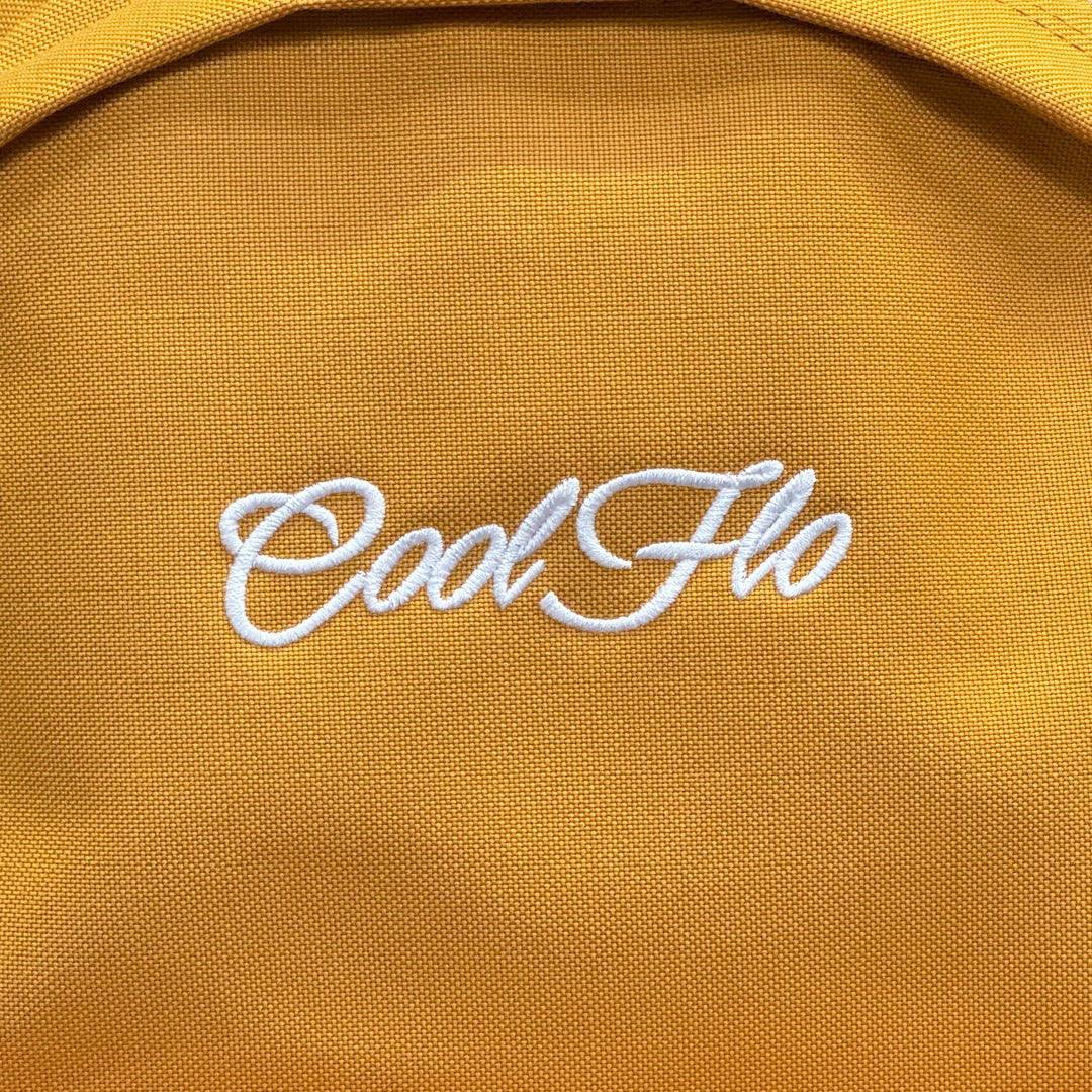 Close-up pic of ~Mustard yellow backpack with embroidered white Cool Flo logo on the front