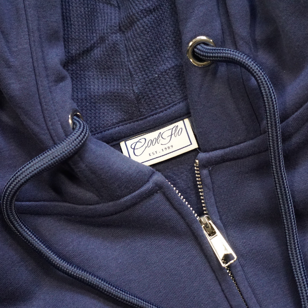 Close-up of neck detail on navy zip-hoody with light grey embroidered Cool Flo script logo on left chest.