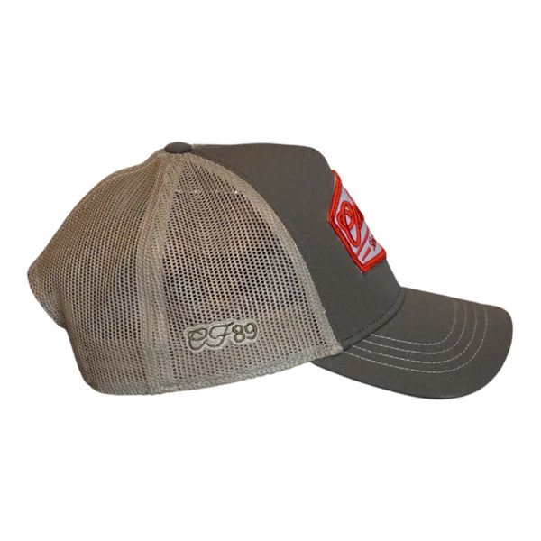 A trucker cap with an olive front and khaki mesh back, featuring a prominent embroidered front patch that reads 'Cool Flo Since 1989' in red and white - side view.
