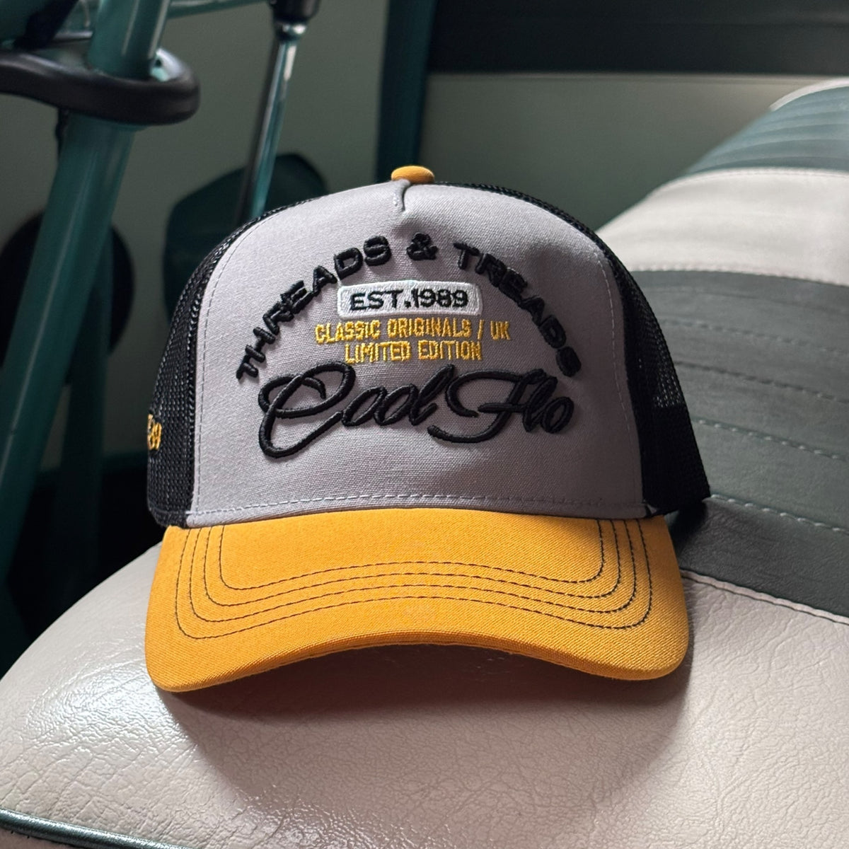 Front view of a Cool Flo Threads & Treads trucker cap in Yellow/Black/White featuring embroidered Threads & Treads artwork with a structured front panel and curved visor