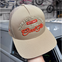 Front view of a Cool Flo Threads & Treads trucker cap in Khaki featuring embroidered Threads & Treads artwork with a structured front panel and curved visor