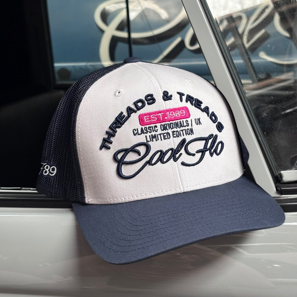Front view of a navy and white Cool Flo Threads & Treads trucker cap with raised embroidered logo and navy curved visor.