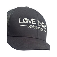 Black trucker cap with embroidered white 'Love Dove Generation' on the front_close up of embroidered logo - close up of logo_side view.