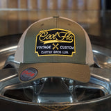 Cool Flo Vintage Custom. Green and khaki trucker cap with embroidered yellow, black and white badge with cross-spanners. Carter Bros. London.