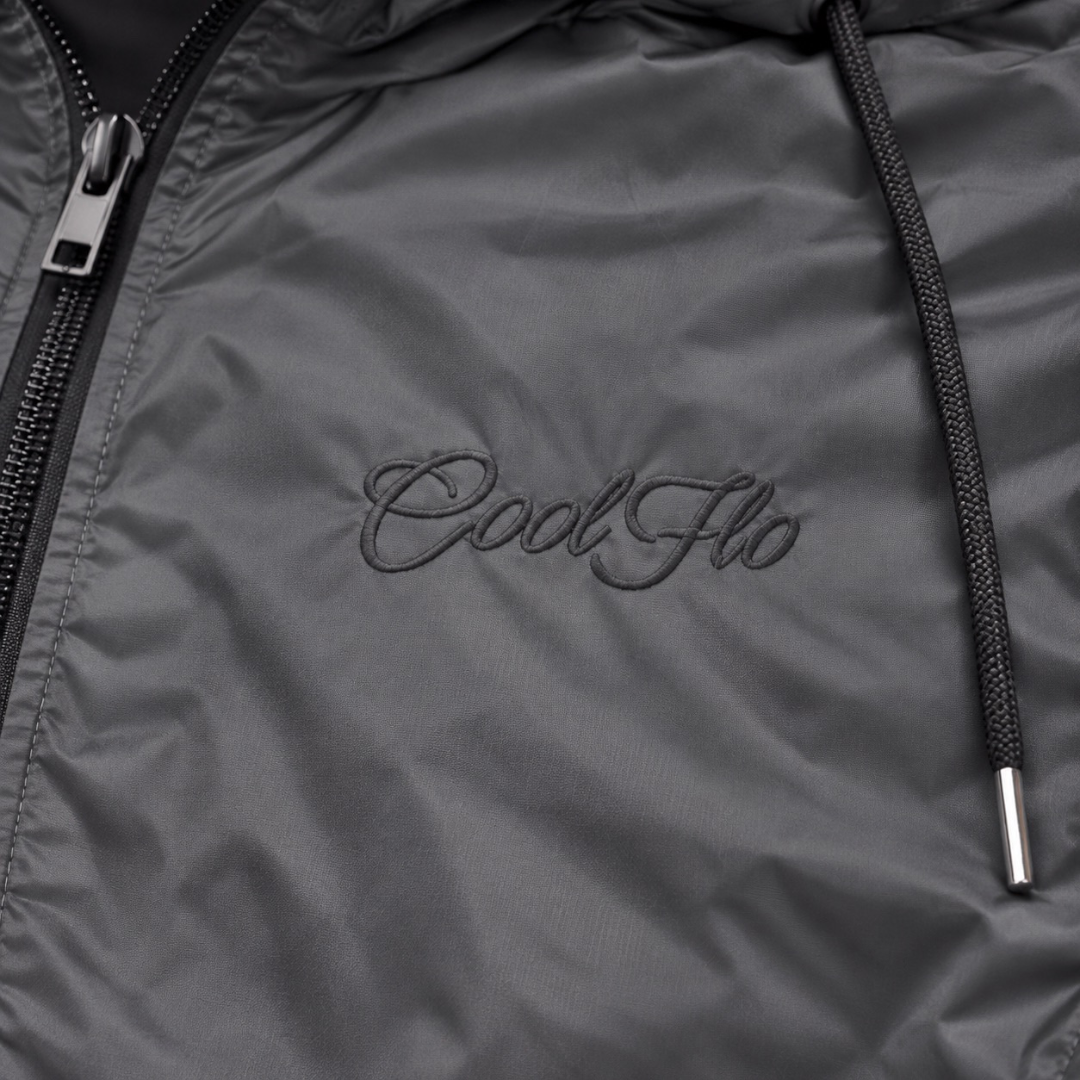 Close-up of tonal Cool Flo Script embroidery on the dark grey Wind Runner Jacket.