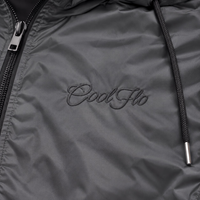 Close-up of tonal Cool Flo Script embroidery on the dark grey Wind Runner Jacket.